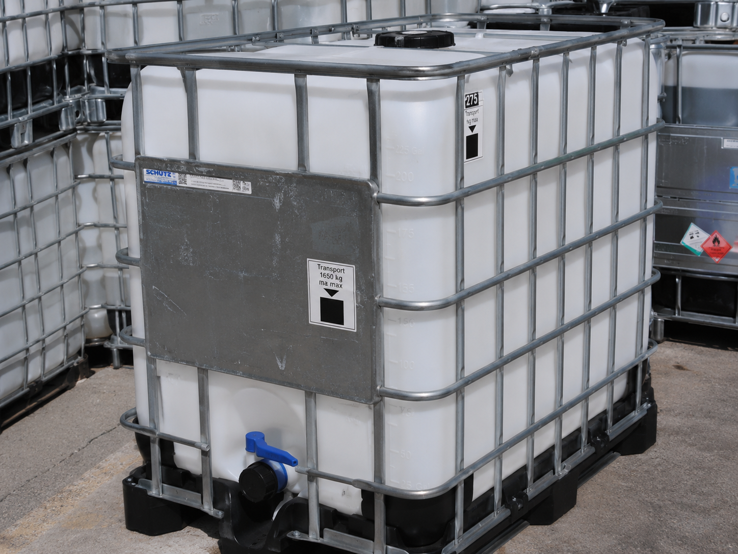 A caged IBC tote showing the discharge valve, fill cap and galvanized steel frame